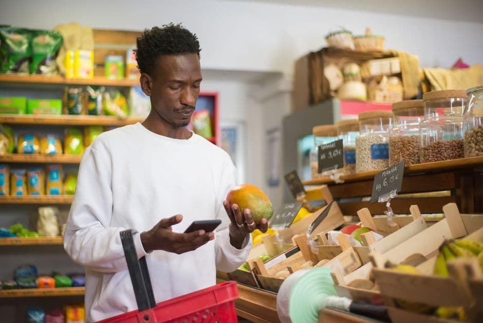 Using a calorie barcode scanner app on a phone to scan a food packet in a supermarket aisle