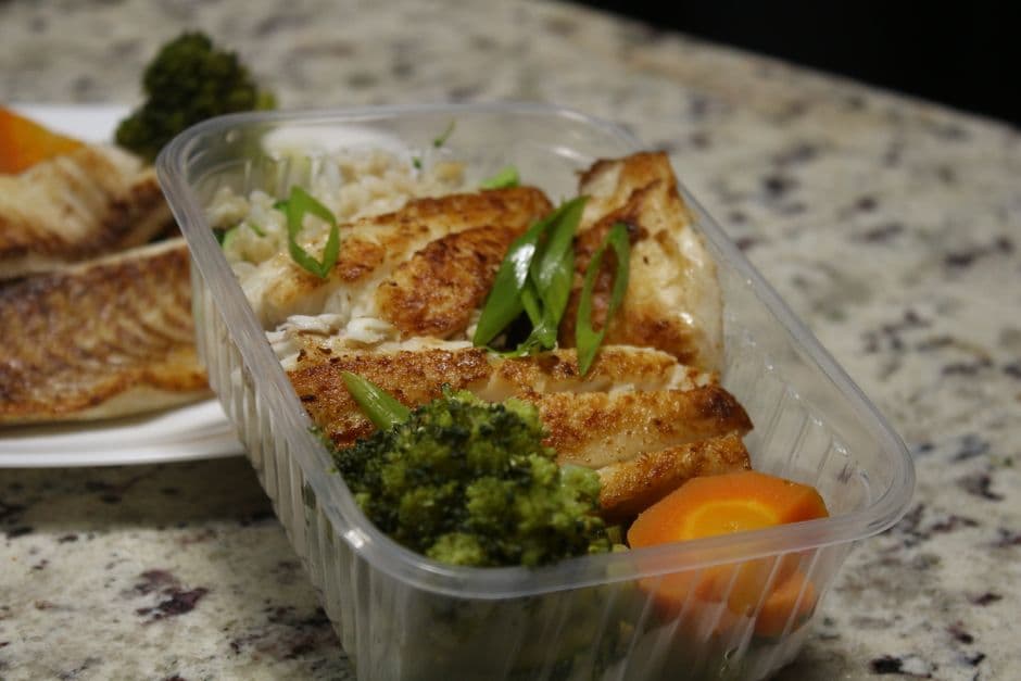 Meal prep containers of grilled chicken, rice and vegetables logged with a calorie counter with a barcode scanner